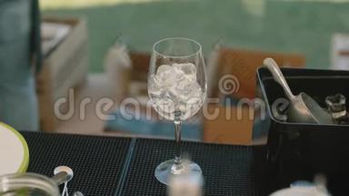 夏日的户外酒吧里，酒吧老板用玻璃玻璃搅动冰块，一杯冰块
